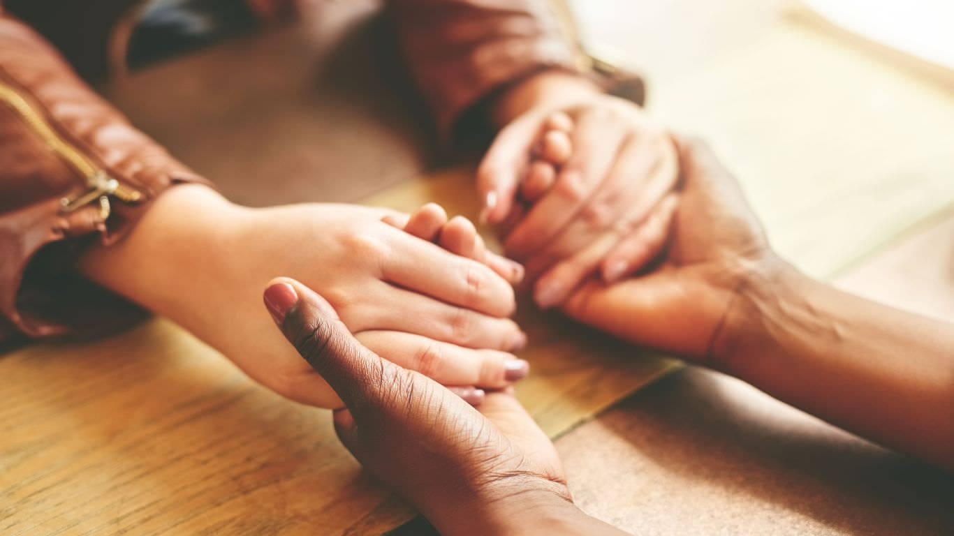 A pair of womens hands holding one another as part of the human need connection